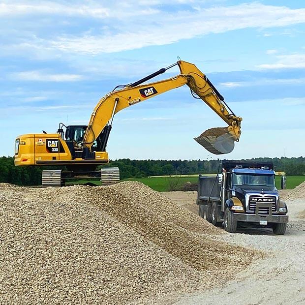 Excavator loading gravel into a dump truck.