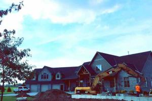 Excavator in front of an upscale home.