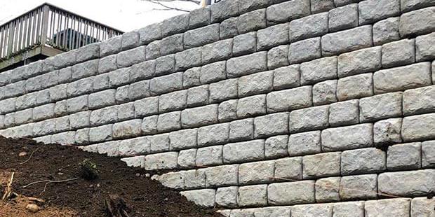 High retaining wall built with white composite stone.